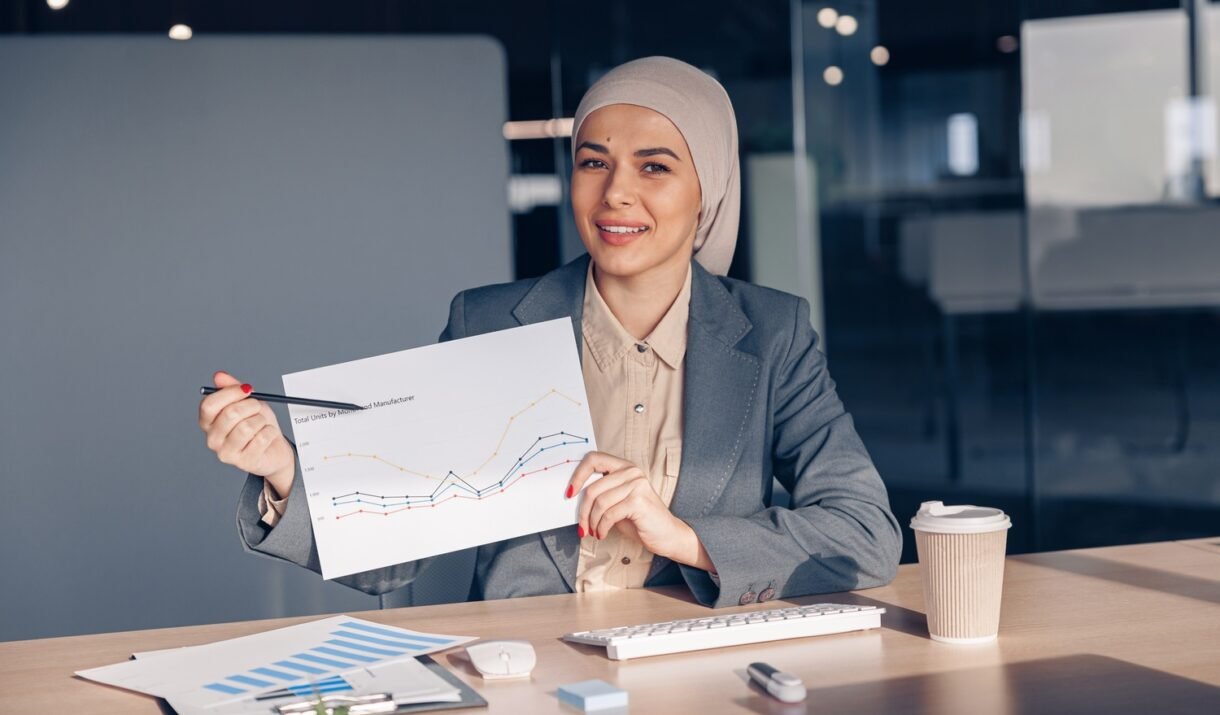 smiling muslim businesswoman in hijab shows a grap amh74w7